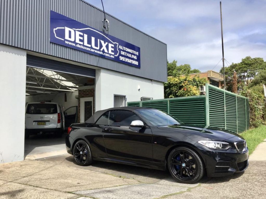 Close-up of luxury car paint showcasing glossy finish and hydrophobic properties after ceramic coating